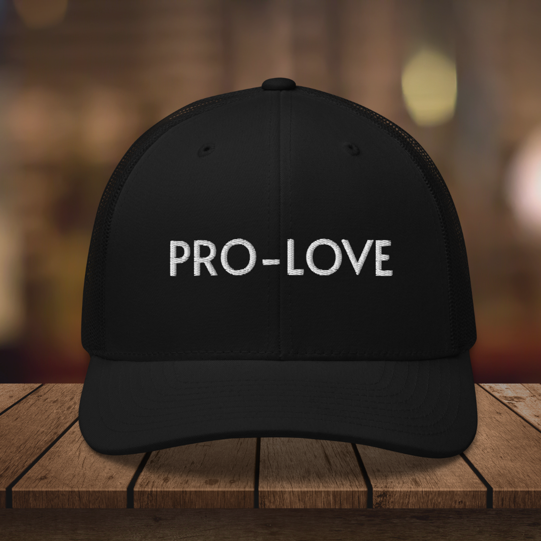 PRO-LOVE| TRUCKER HAT| FEEL THE FACTS A front view of the Pro-Love Trucker Hat, featuring the embroidered "Pro-Love" logo on the front and a stylish mesh design on the sides. BLK