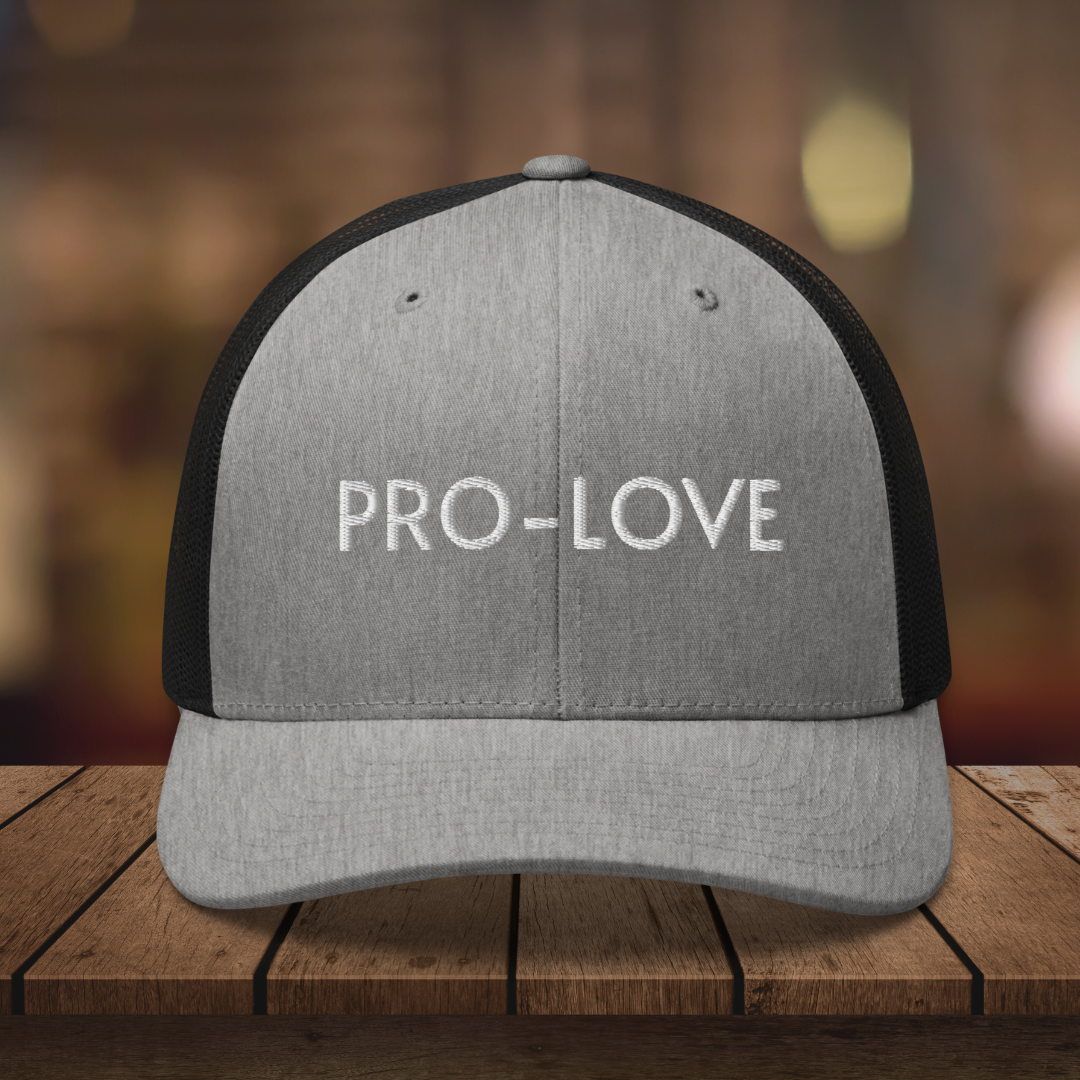 PRO-LOVE| TRUCKER HAT| FEEL THE FACTS A front view of the Pro-Love Trucker Hat, featuring the embroidered "Pro-Love" logo on the front and a stylish mesh design on the sides. BLK_GRY