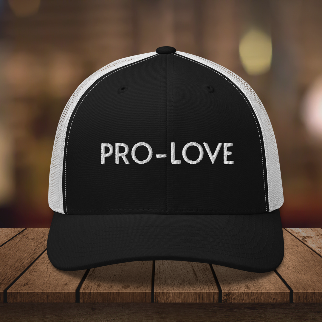 PRO-LOVE| TRUCKER HAT| FEEL THE FACTS A front view of the Pro-Love Trucker Hat, featuring the embroidered "Pro-Love" logo on the front and a stylish mesh design on the sides. BLK_WHT