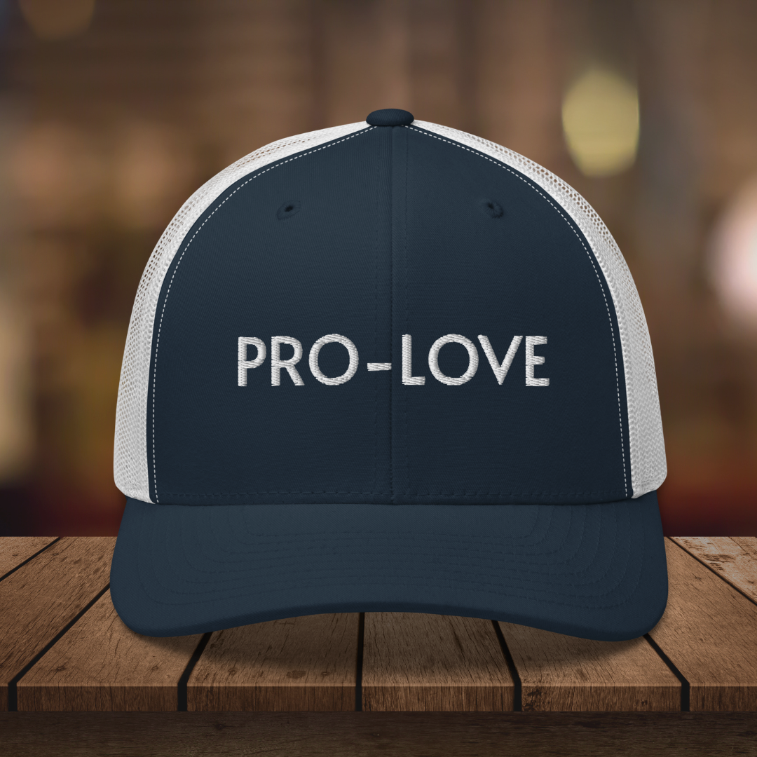 PRO-LOVE| TRUCKER HAT| FEEL THE FACTS A front view of the Pro-Love Trucker Hat, featuring the embroidered "Pro-Love" logo on the front and a stylish mesh design on the sides. BL_WHT